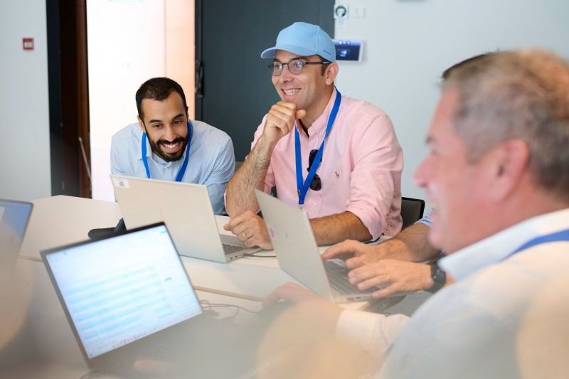 Arman coaching Capgemini executives at a table with laptops